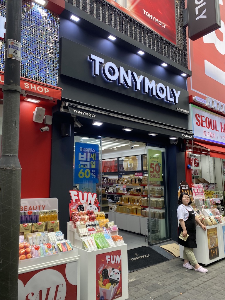 Outside TONYMOLY with a female worker standing near the products.