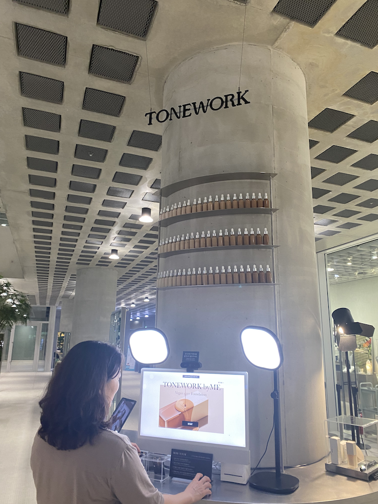 A woman discovering a product color that matches her skin tone on the computer at TONEWORK.